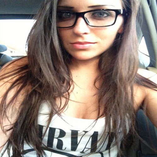 Young woman with long brown hair and glasses wearing a Nirvana t-shirt.