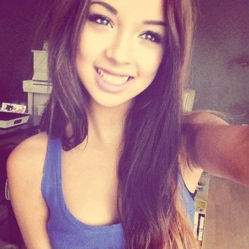 A young woman with long brown hair smiles brightly at the camera.