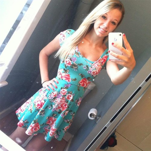 Young pretty woman in a floral dress takes a selfie in a mirror.