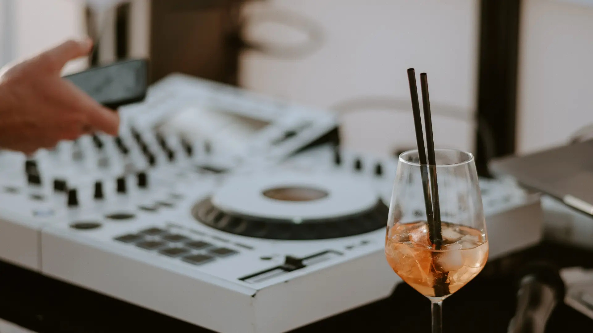 Ein Getränk im Glas mit einem weißen DJ-Mischpult im Hintergrund