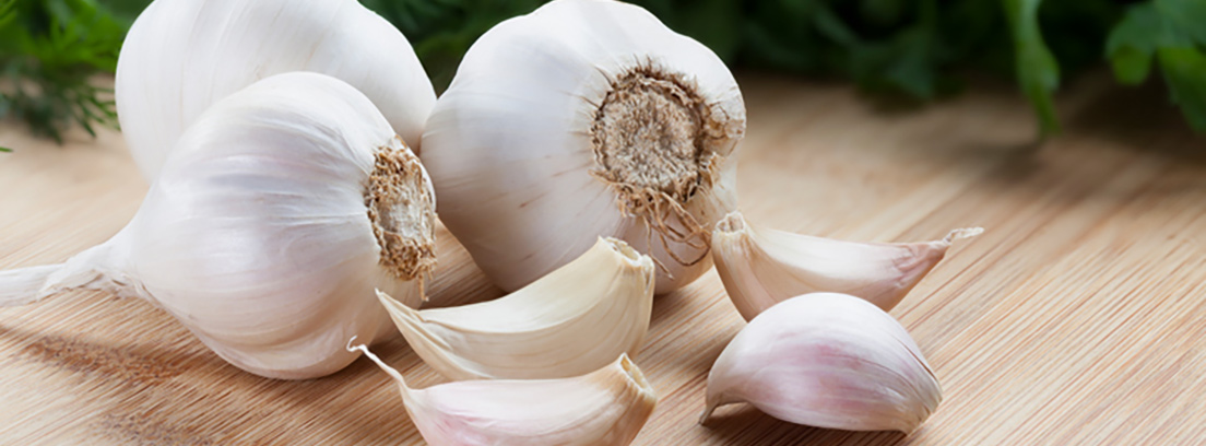Fresh garlic bulbs and cloves on a wooden surface.
