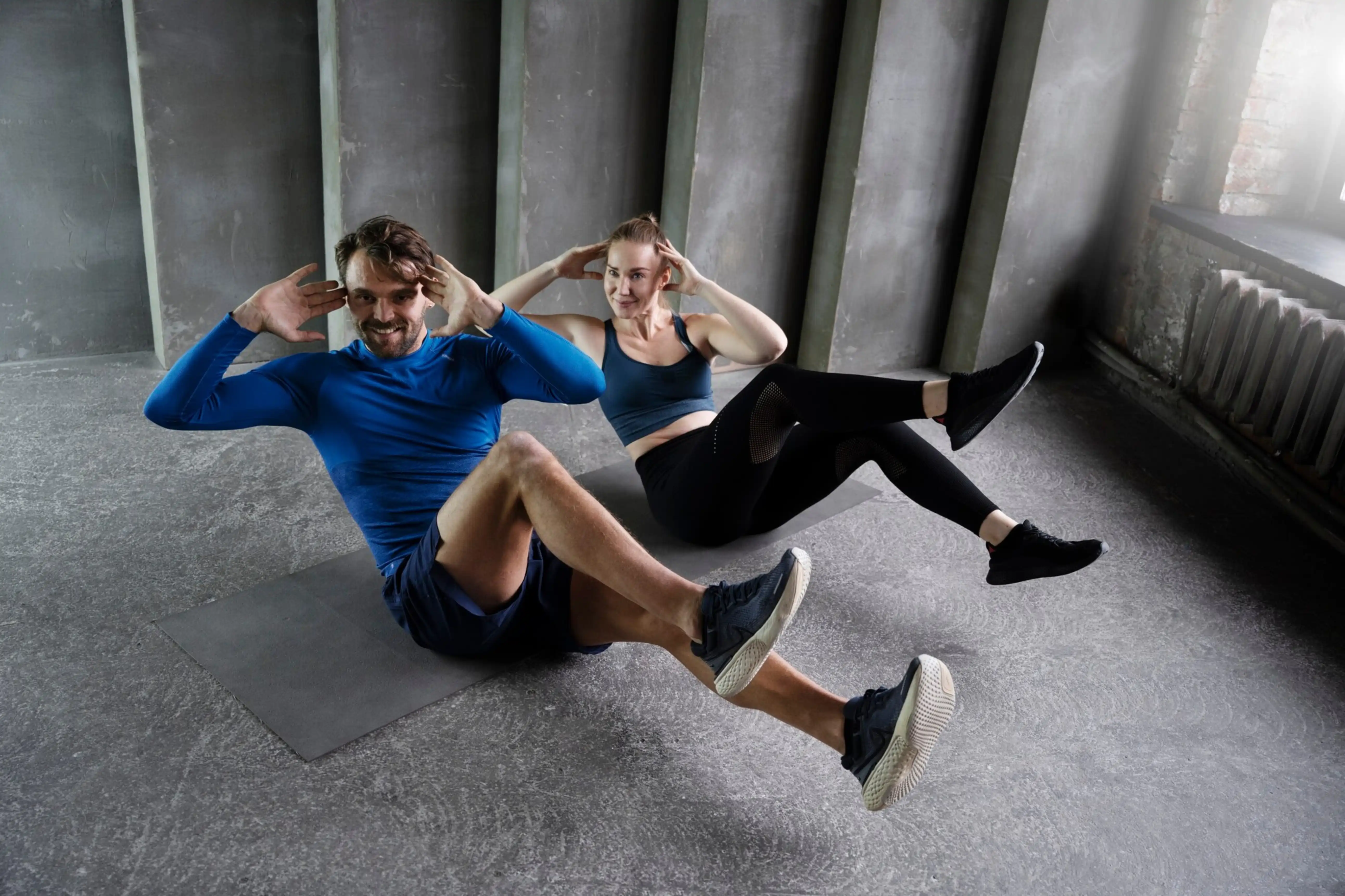 Two people exercising on mats in a gym setting.