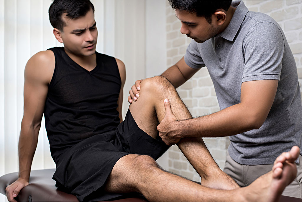 Physiotherapist examining a patient's knee in a clinic.