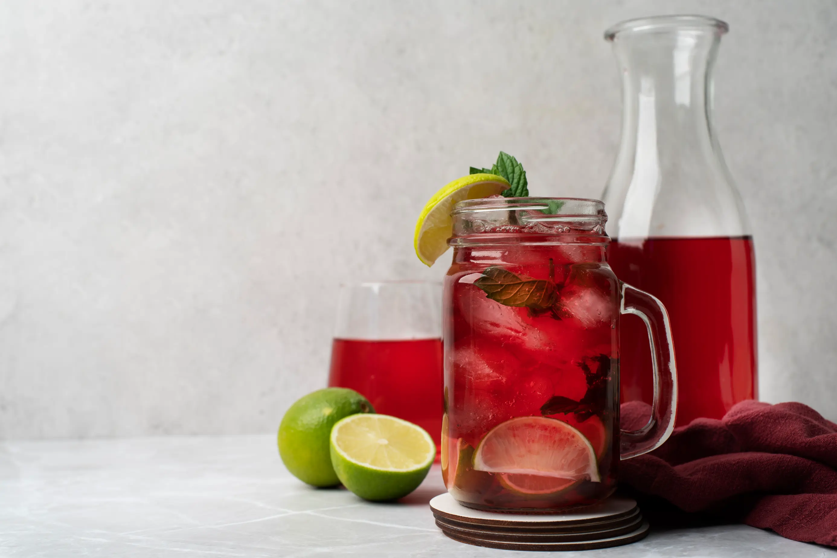 Refrescante bebida de jamaica con hielo, lima y menta en un tarro de cristal.
