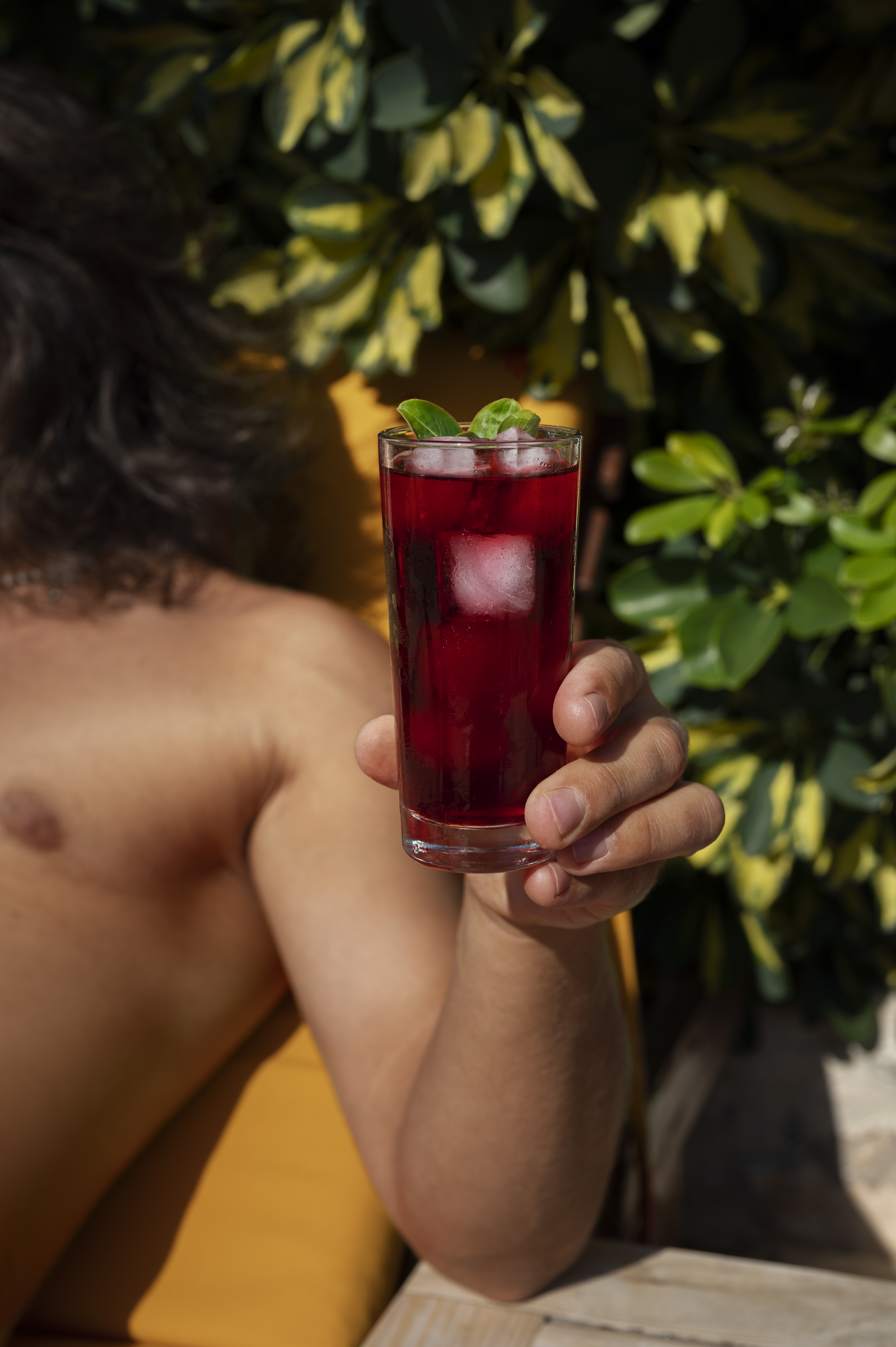 Una persona sostiene un vaso alto de bebida de jamaica helada.