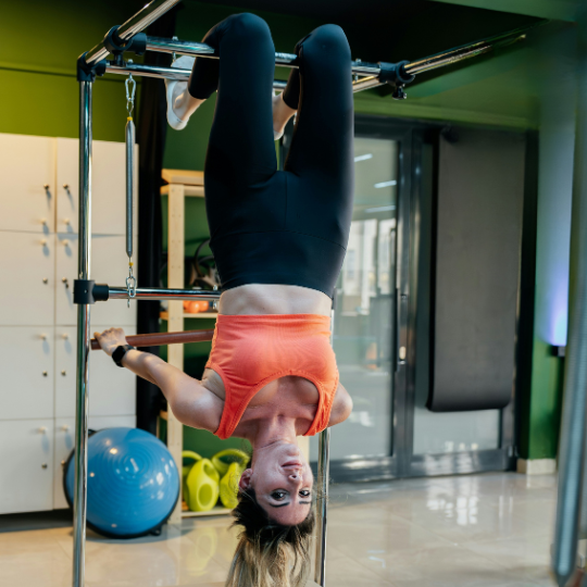Woman hanging upside down from pull up bar in the gym..