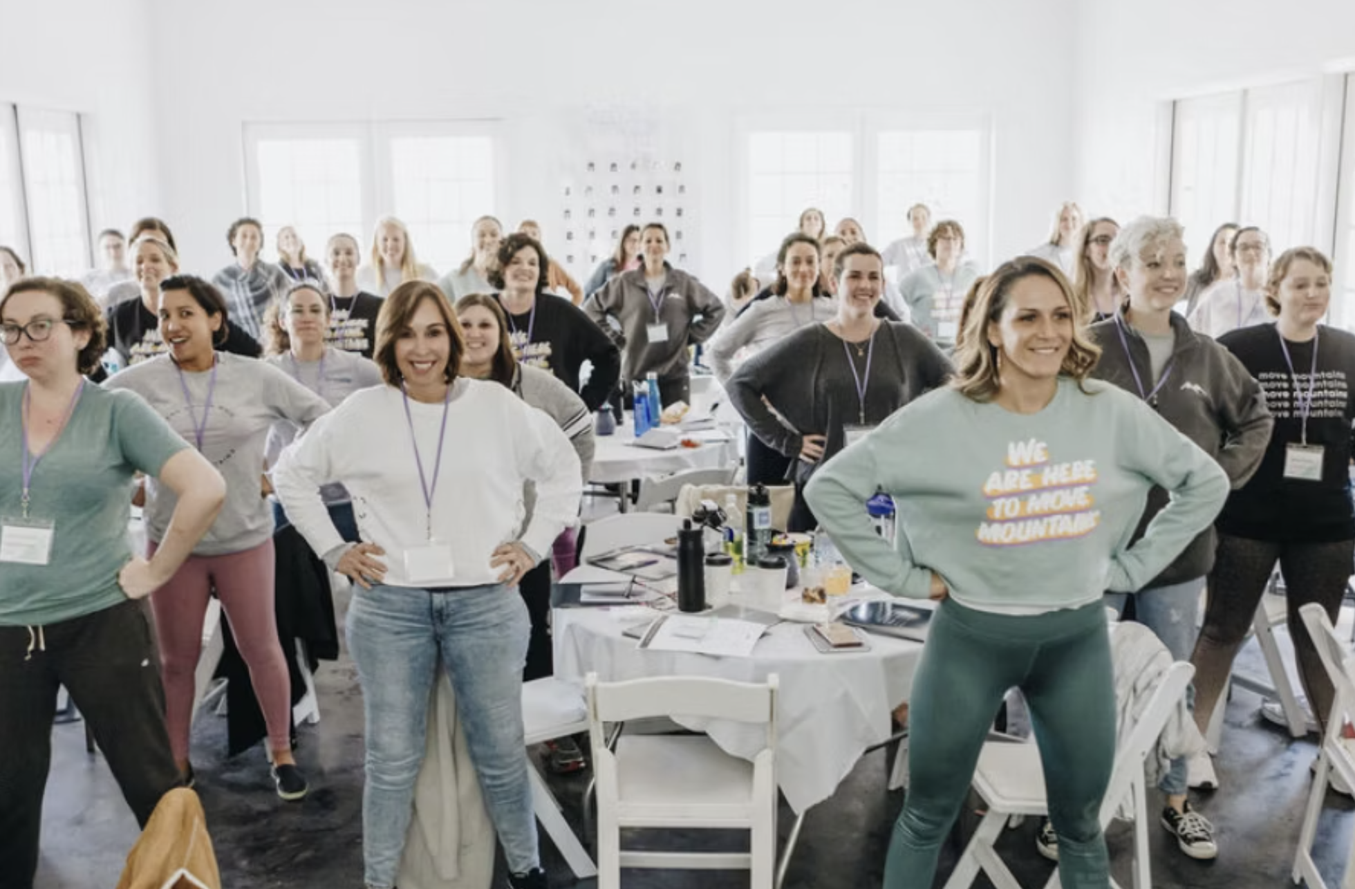 A group of women in casual athletic wear stand with hands on hips.