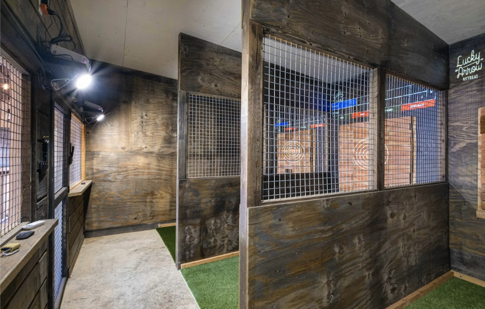 Axe throwing lanes with wooden walls, targets, and safety cages.