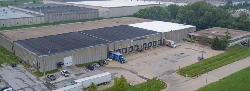 Aerial view of a large warehouse with trucks and parking.