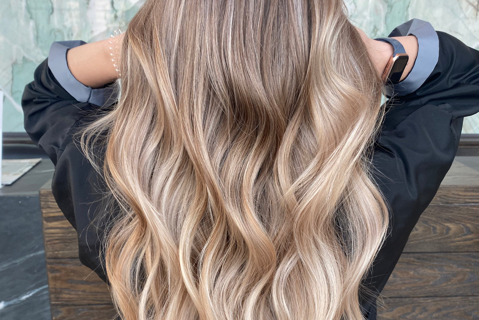 A close-up of wavy, highlighted hair from behind.