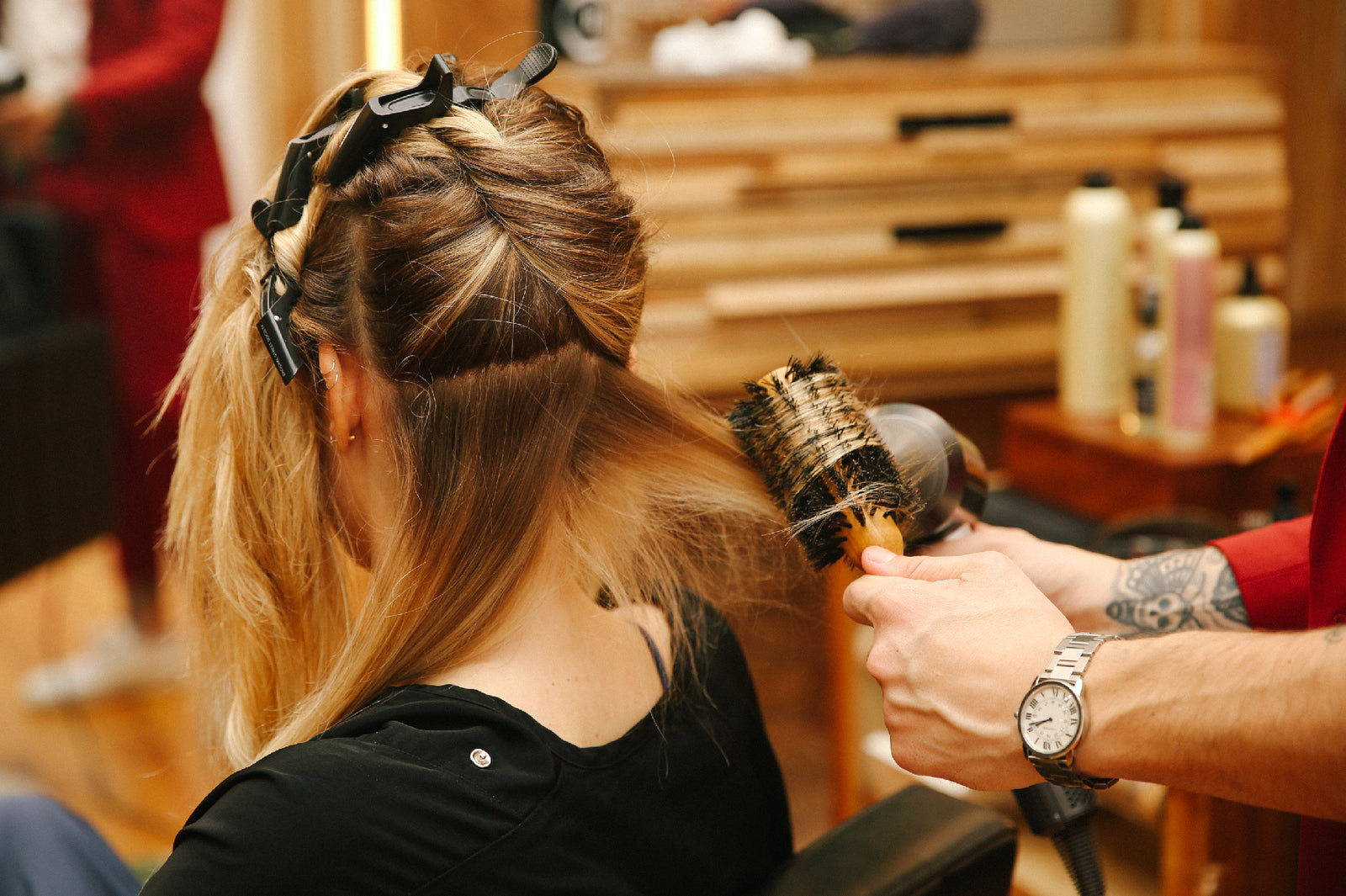 Stylist using round brush on client's hair in salon.