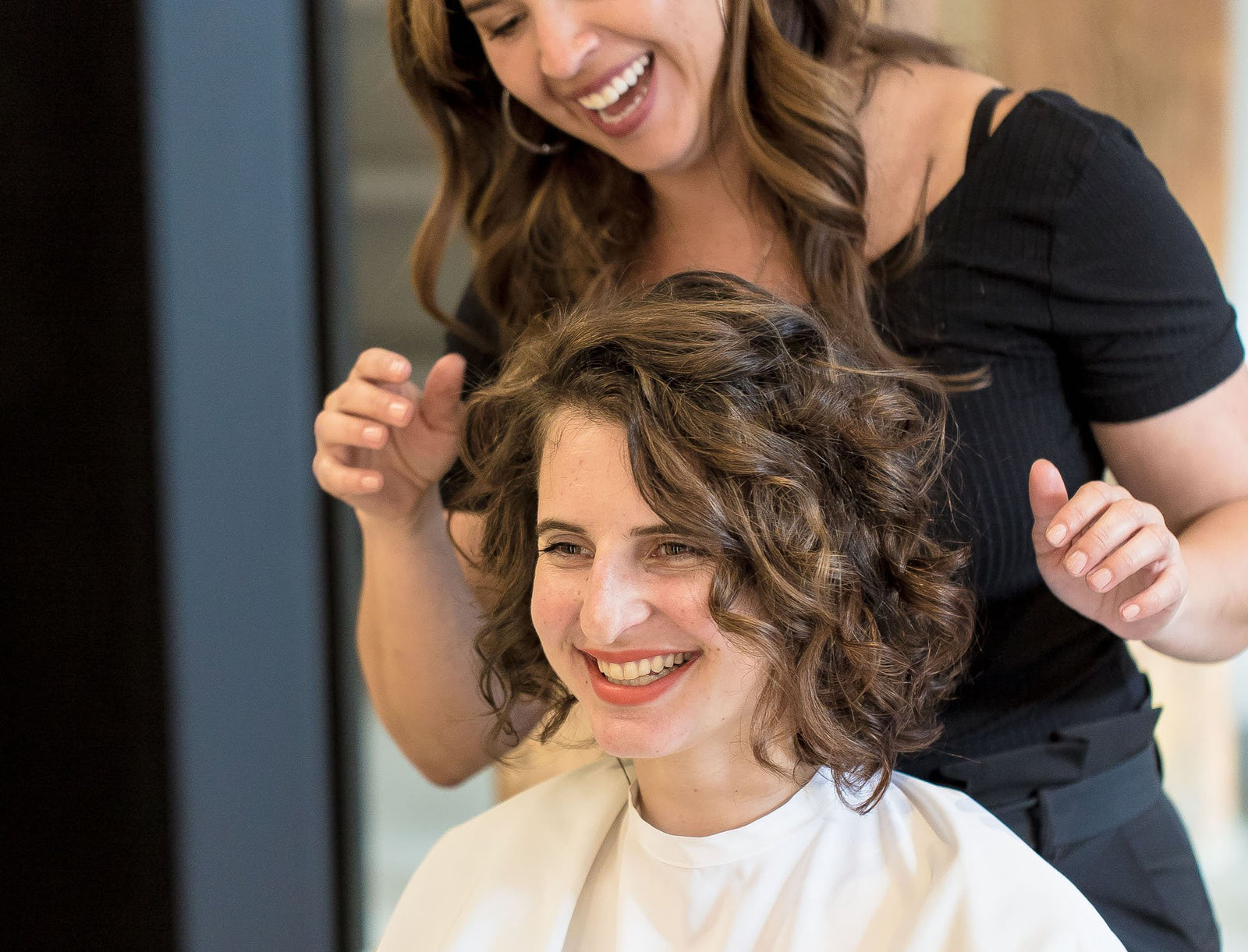 Woman with natural curls receiving polished hair styling