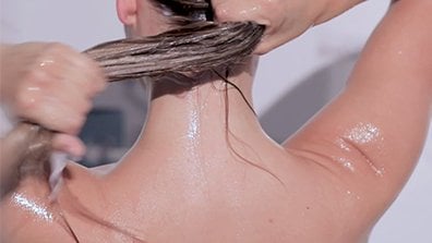 Person lathering shampoo in a shower